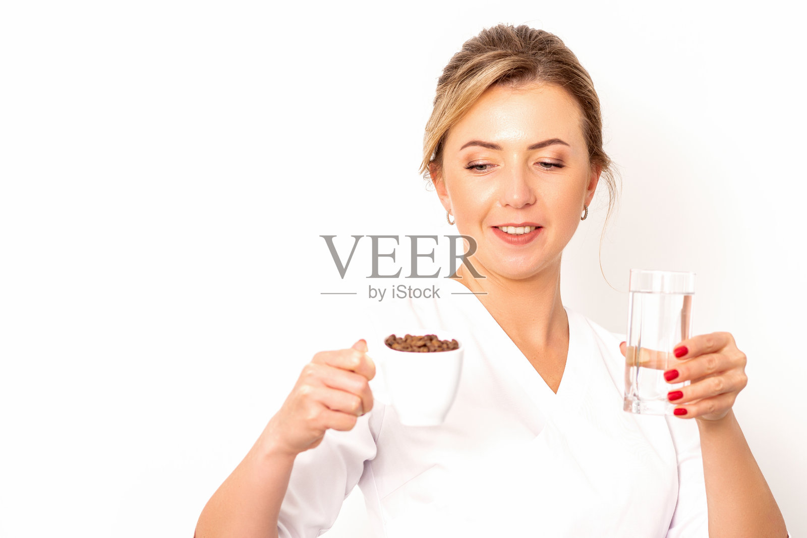 加水的咖啡。女营养师手里拿着一杯咖啡豆和一杯水,背景是白色的。照片摄影图片