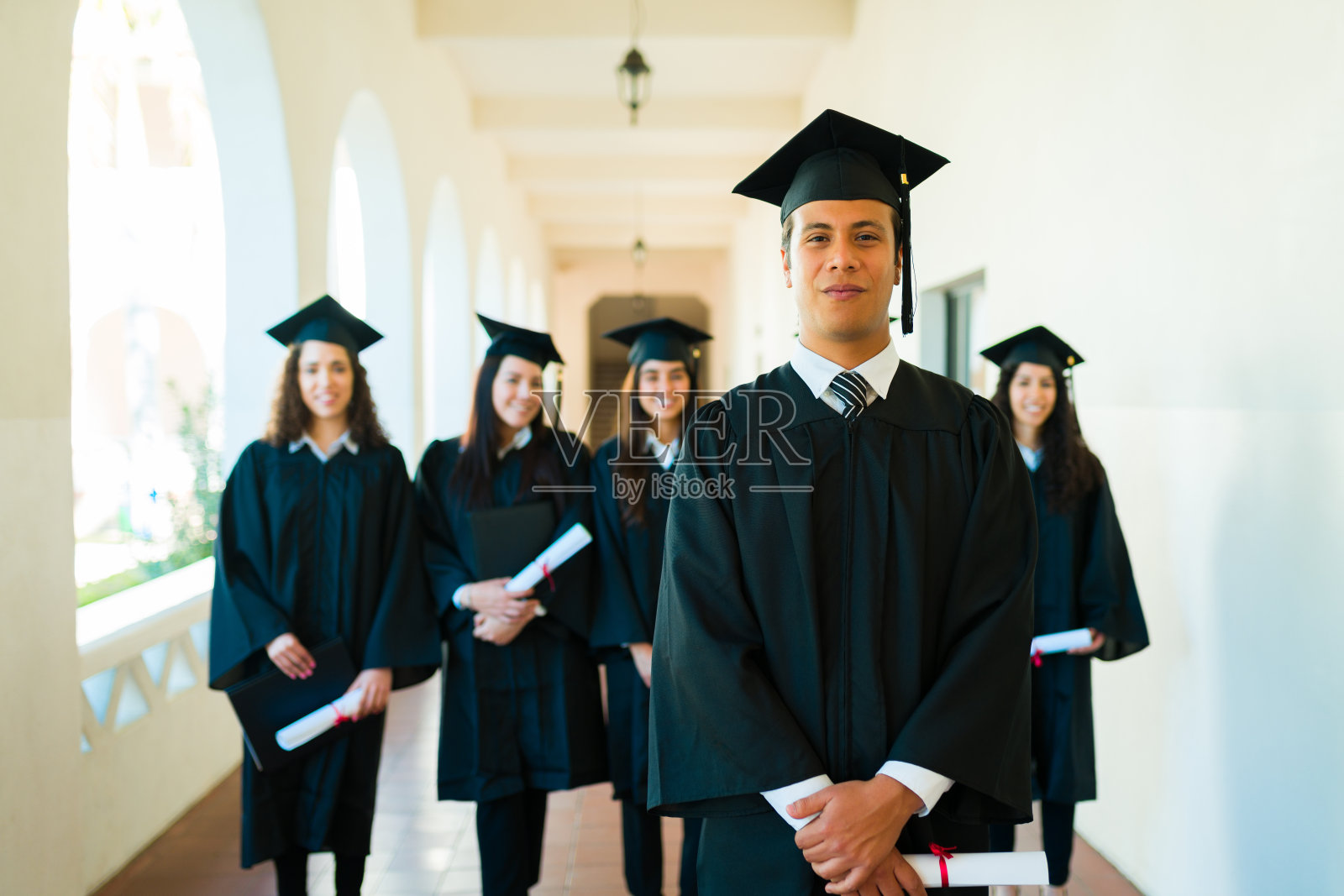 穿着毕业礼服的帅哥毕业生眼神交流照片摄影图片
