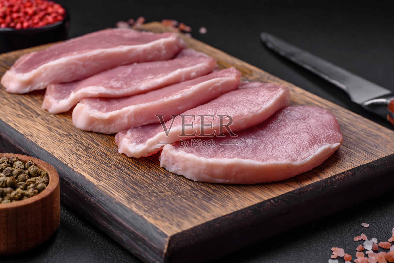 新鲜多汁的猪肉放在木砧板上,加上香料和盐照片摄影图片