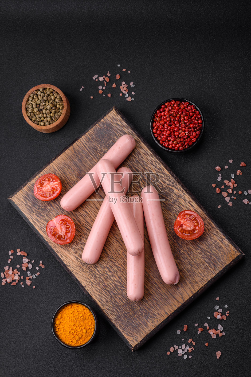 煮香肠放在木砧板上,配上西红柿、香料和盐照片摄影图片