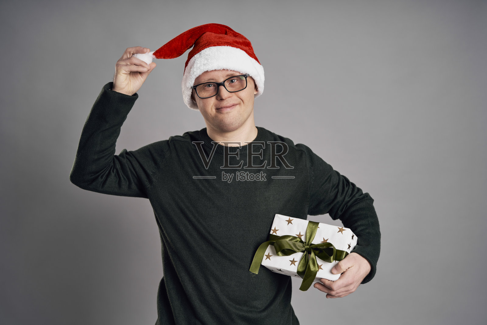 戴着圣诞帽并拿着圣诞礼物的唐氏综合征男人照片摄影图片
