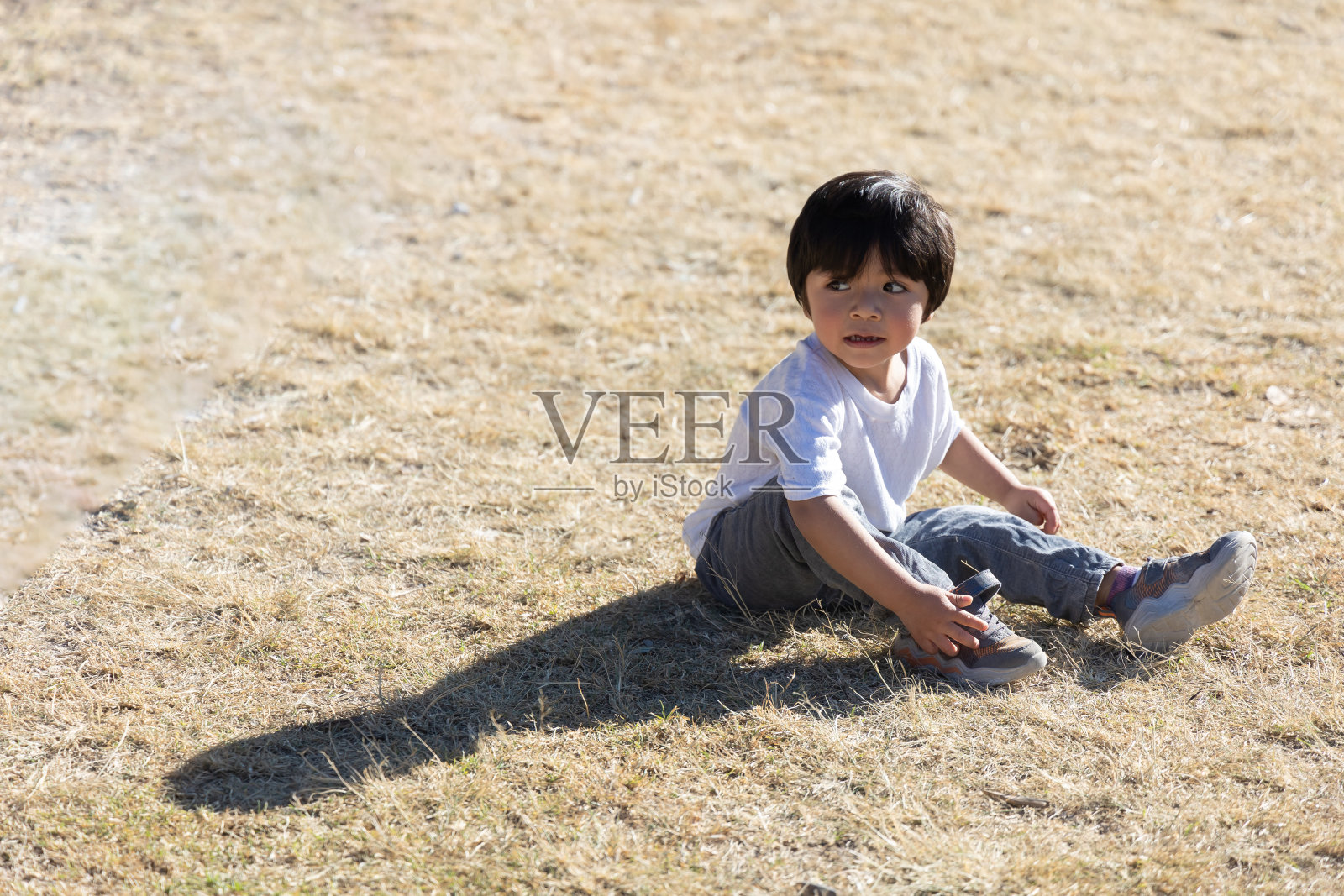 三岁的墨西哥男孩坐在黄色的草地上照片摄影图片