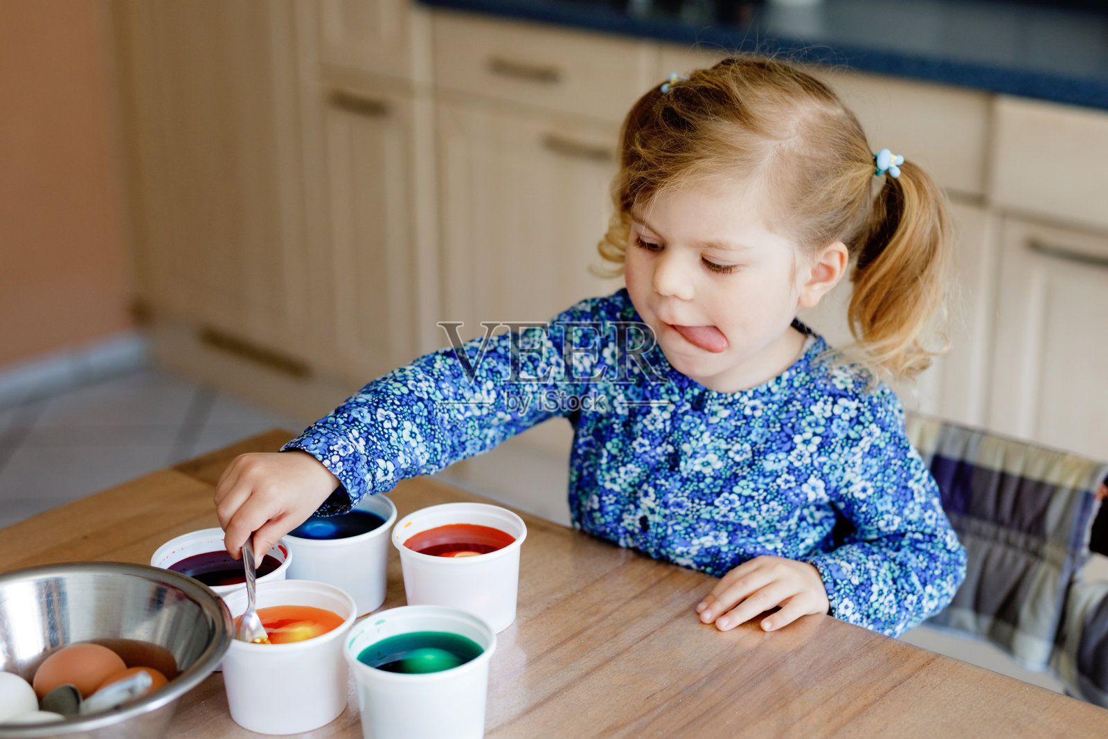 兴奋的小女孩为复活节涂彩蛋。可爱的快乐的孩子看着五颜六色的鸡蛋惊讶,与家人庆祝节日。可爱的孩子在家里与不同的明亮的颜色。照片摄影图片