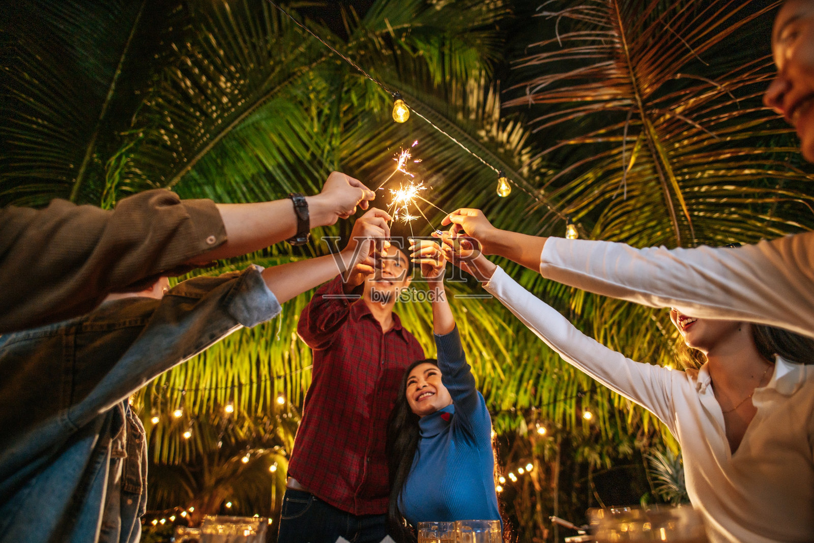 快乐的亚洲一群朋友在户外玩烟花的肖像-年轻人在晚上玩烟花-人,食物,饮料的生活方式,新年庆祝概念。照片摄影图片