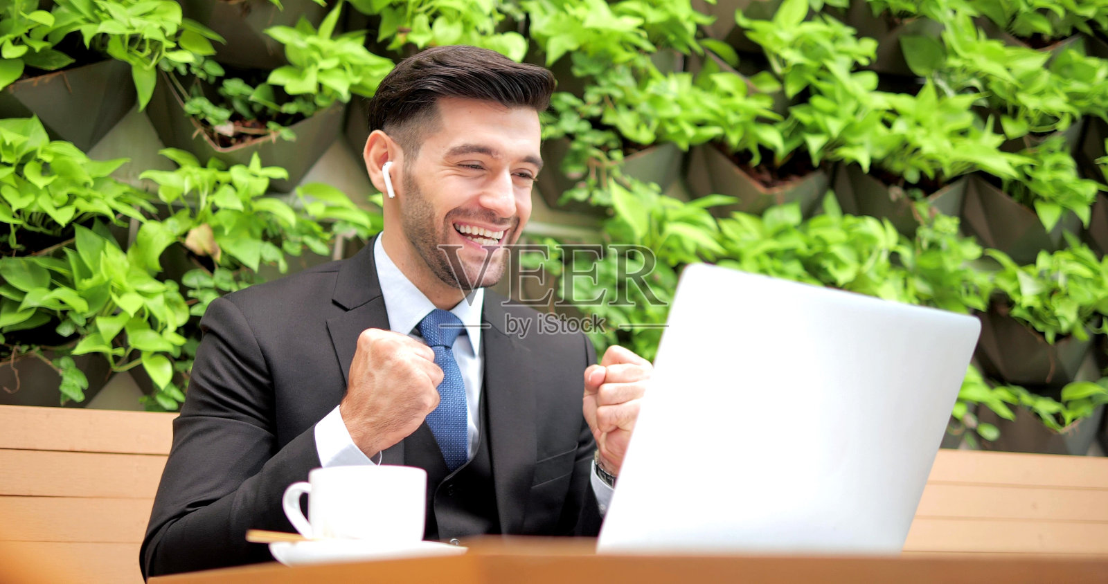 帅气的商人穿着正装坐在咖啡馆餐厅,打开笔记本电脑,与商业伙伴交谈照片摄影图片