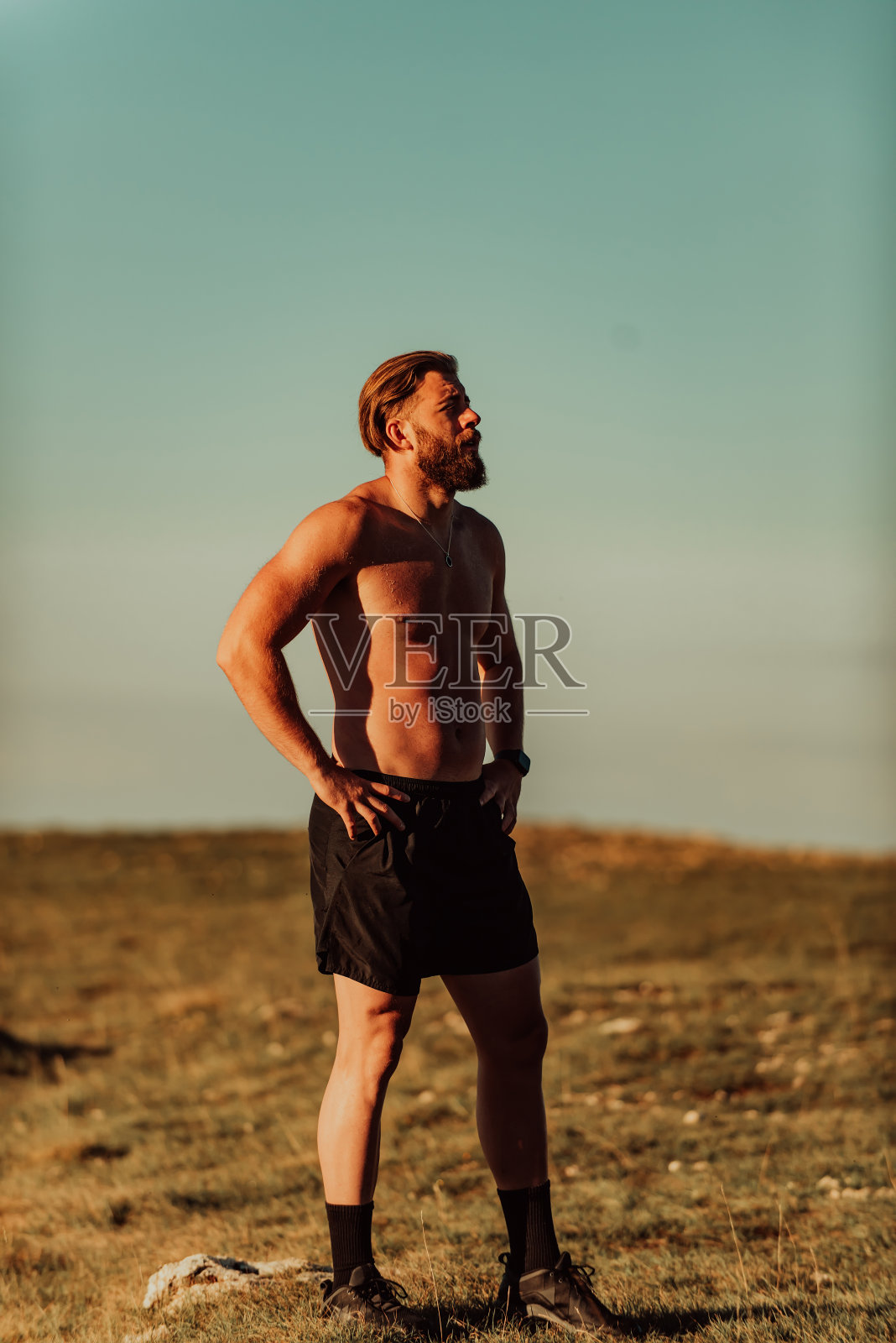 一名运动员在疲惫的跑步训练后在山顶休息。照片摄影图片