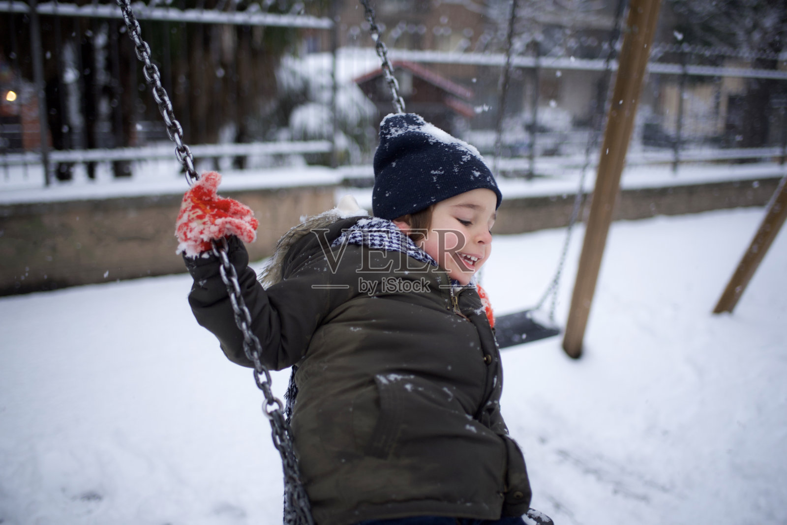 男孩在雪地里荡秋千照片摄影图片