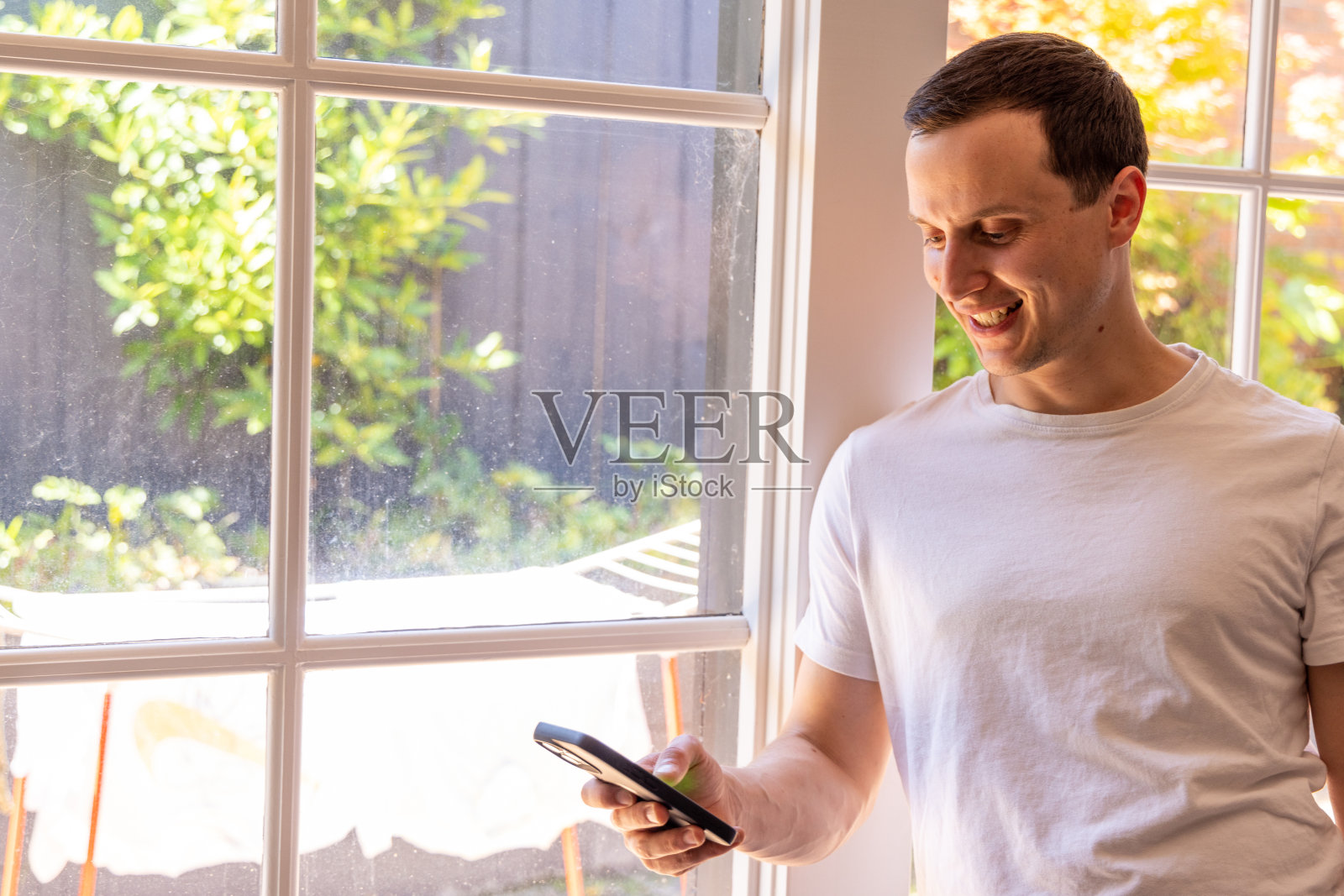 快乐的男人在家使用无线技术,使用手机照片摄影图片