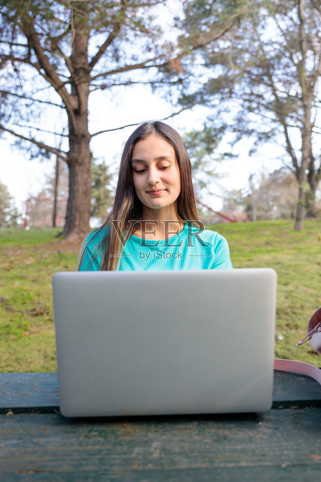 一名女大学生坐在公园外,用笔记本电脑学习。照片摄影图片