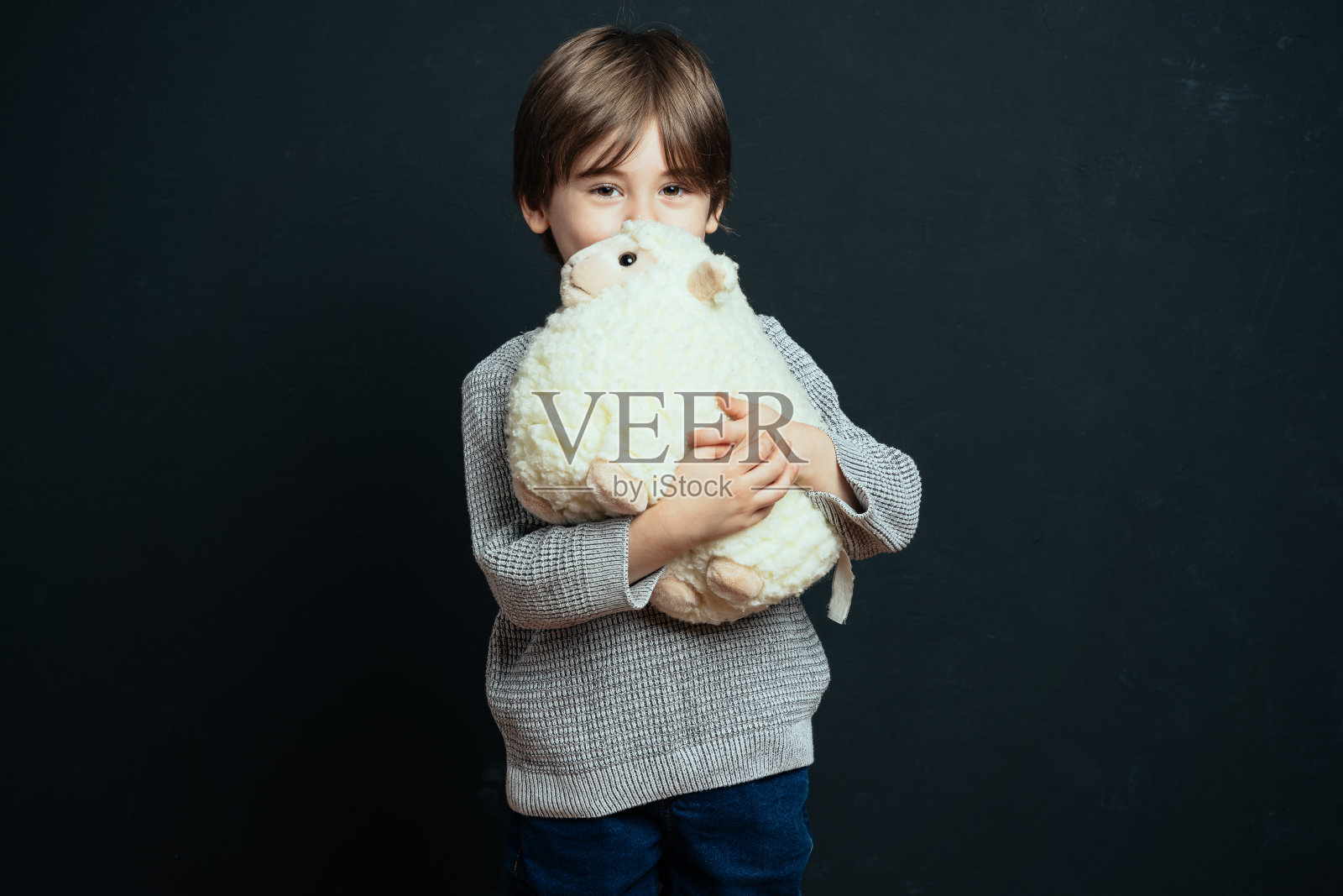 小男孩抱着他的毛绒玩具小羊照片摄影图片