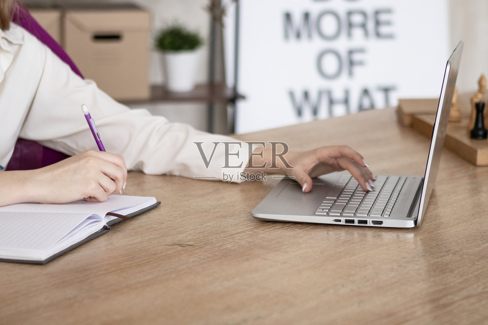 金发长发的年轻女孩坐在办公室的办公桌前,用电脑工作,写日记。照片摄影图片