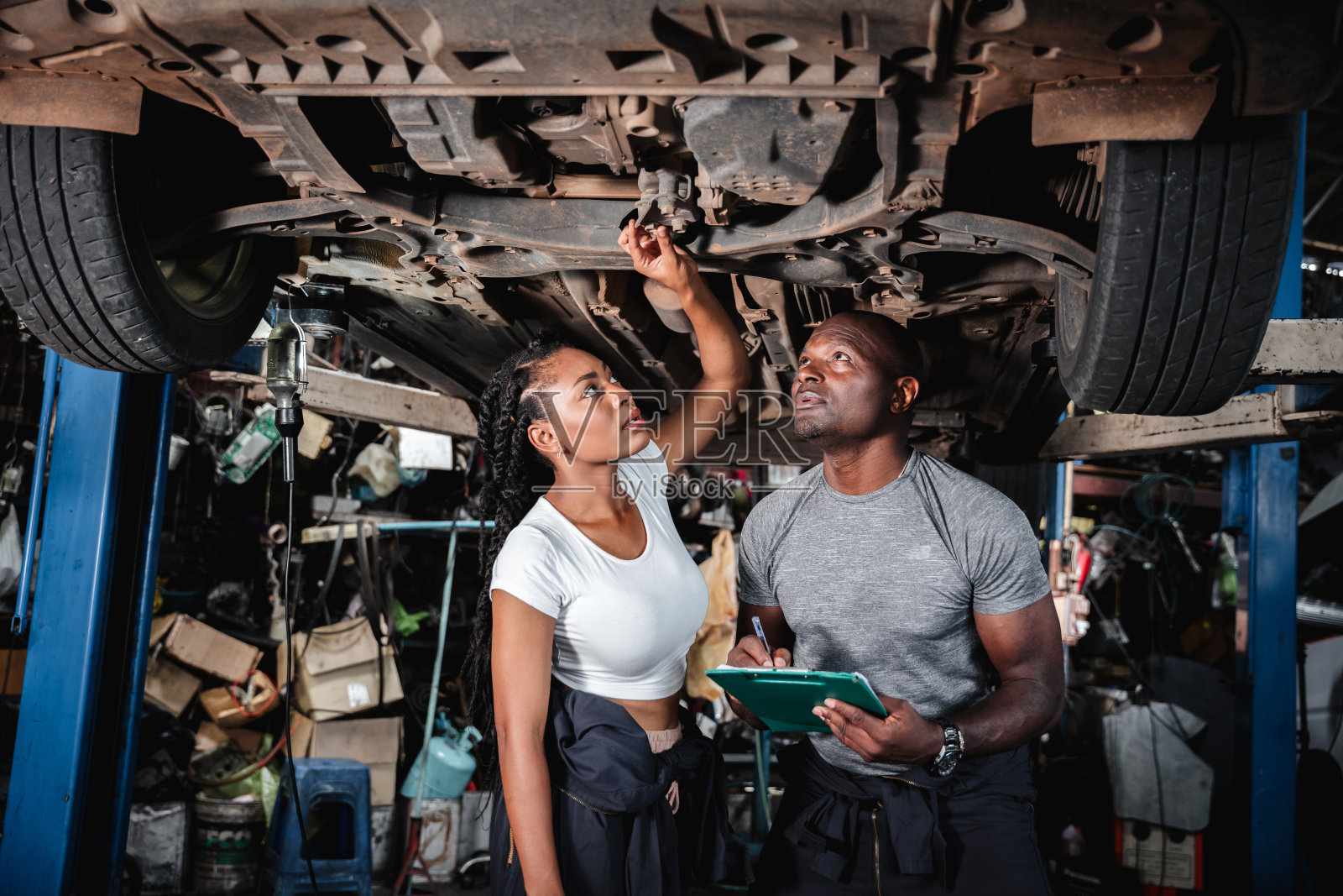 两名机械师在车库里检查和核对车底的零件。修车服务理念照片摄影图片