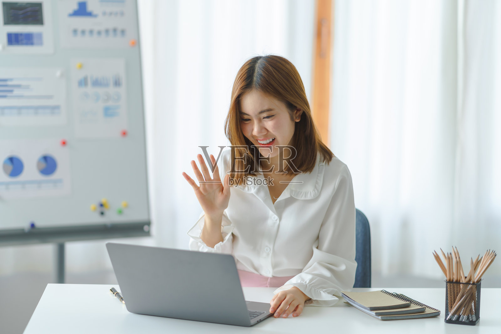 年轻美丽的亚洲女商人坐着看网络摄像头,看着摄像头,在虚拟会议或视频通话交谈。照片摄影图片
