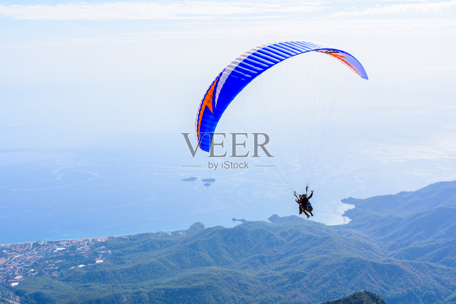 在空中滑翔。滑翔伞串联飞越大海和山脉。极限运动照片摄影图片