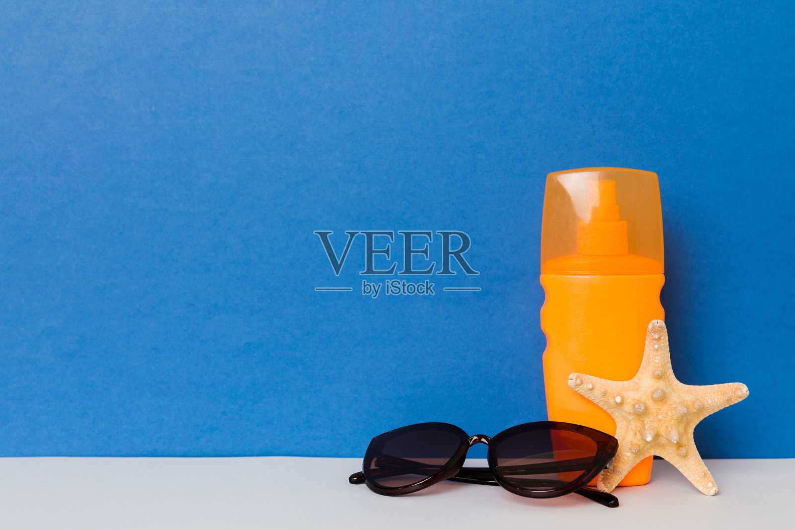 海滩配件。保湿防晒防晒乳液瓶在夏季的UVB护肤保护与贝壳在彩色背景。模拟复制空间照片摄影图片