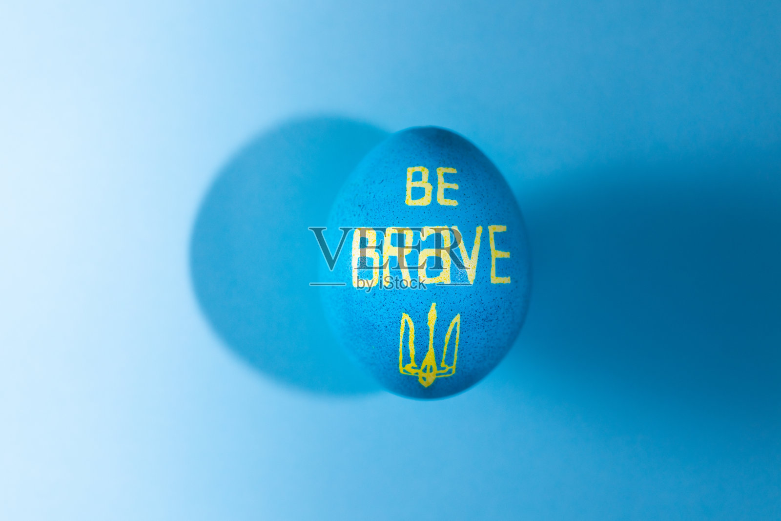 用蓝色和黄色画的复活节彩蛋,上面写着“要勇敢”照片摄影图片