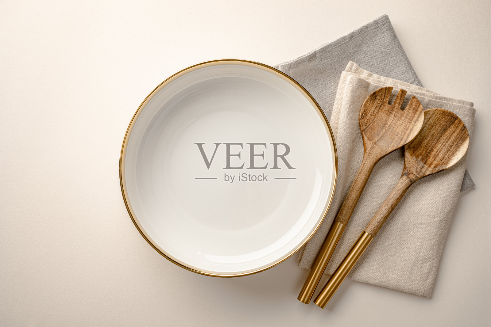 空奶油色沙拉碗,桌上有亚麻餐巾和木制餐具照片摄影图片