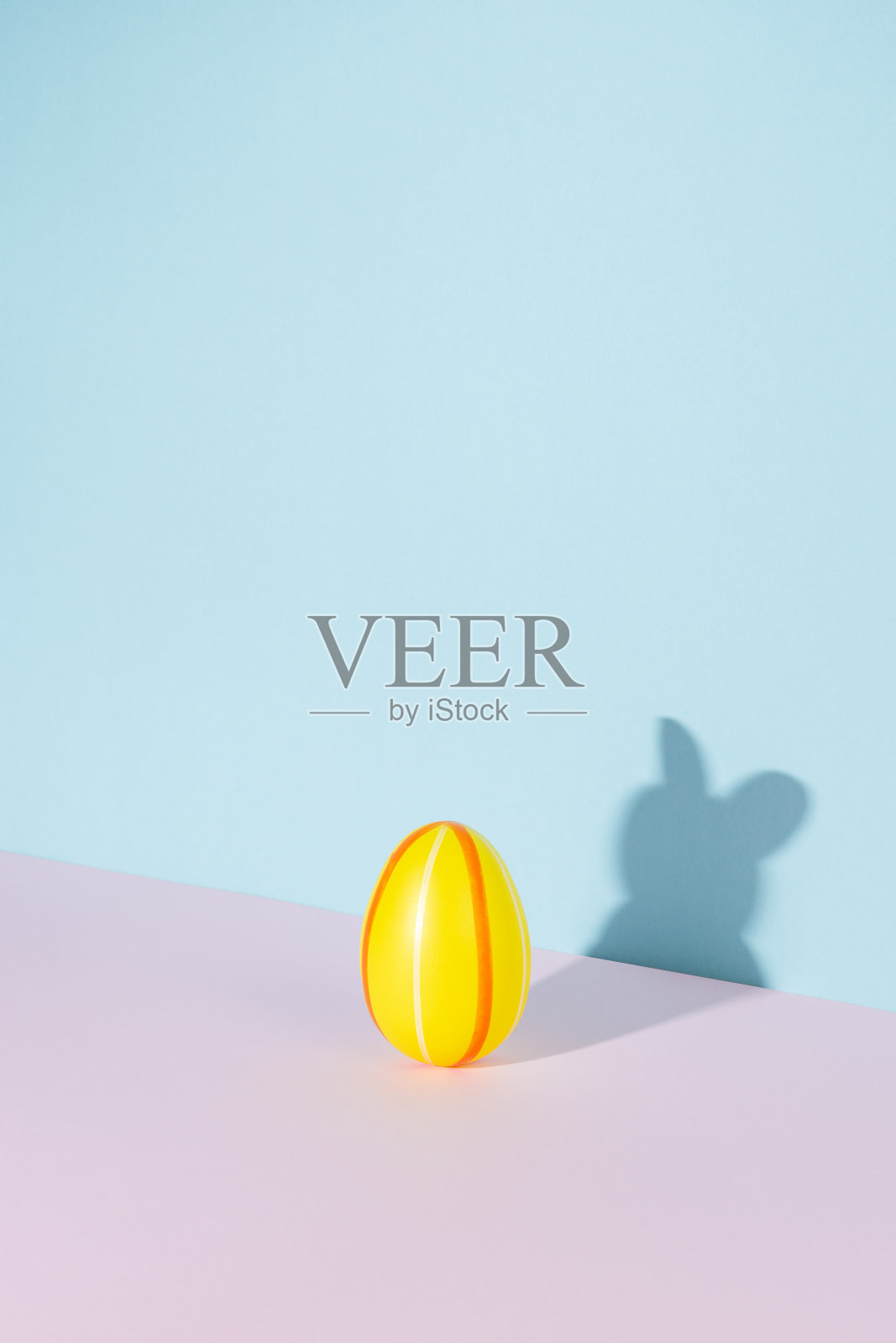 复活节彩蛋的影子在兔子或兔子的形状在粉彩的粉红色和蓝色的背景。最小的复活节概念。照片摄影图片