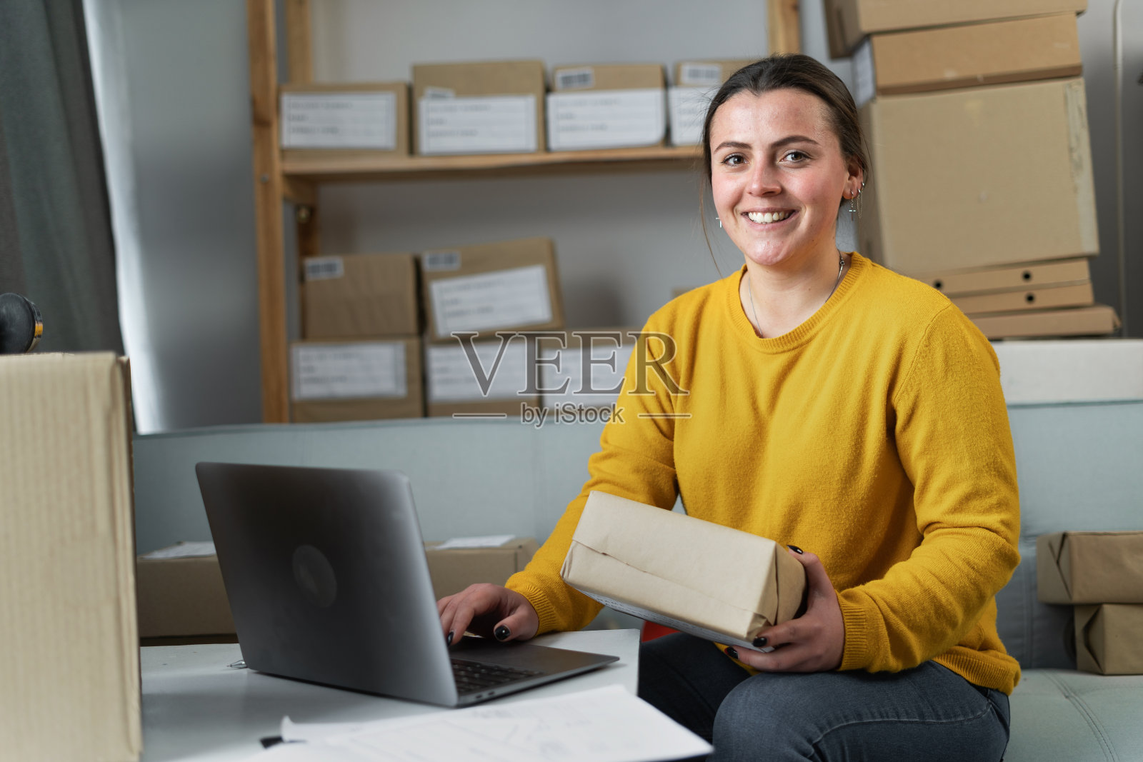 创业小公司的企业家或自由职业者快乐的女人使用笔记本电脑,年轻的成功女性与盒子看着相机,在线营销包装盒和交付,中小企业的概念。照片摄影图片