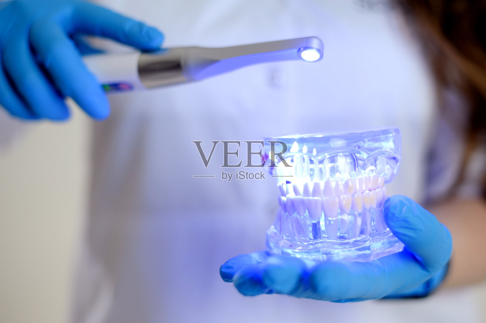 光聚合物灯医生仙女与发光的蓝色灯在白色医疗服牙医治疗牙齿义肢治疗牙龈龋齿美女广告牙科诊所最新技术照片摄影图片