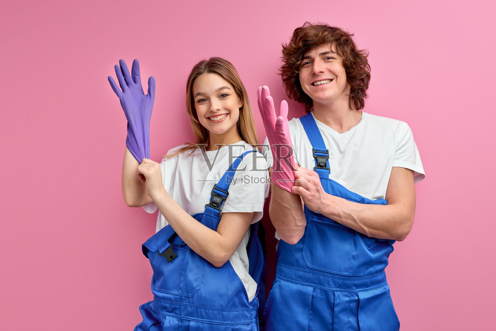 一起打扫卫生很有趣。微笑的男人和女人穿着工作服,戴着橡胶手套照片摄影图片