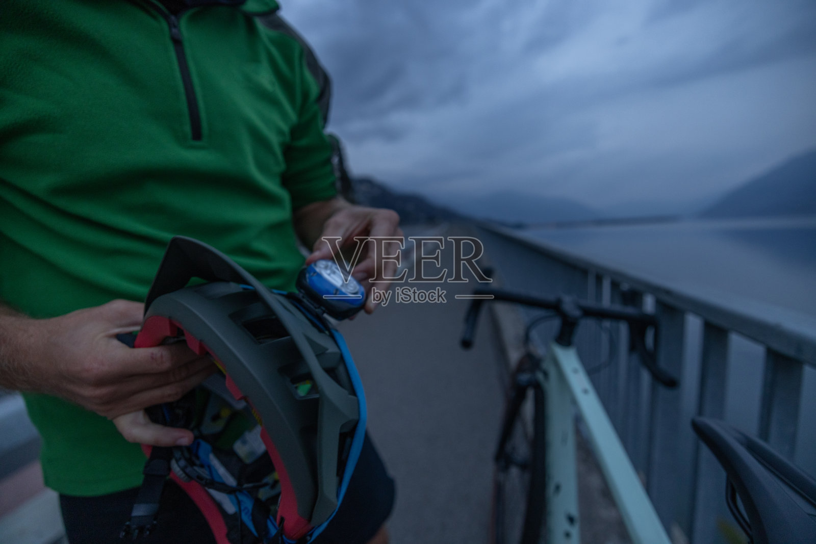 一个面目全非的自行车手把他的头灯调整到头盔上照片摄影图片