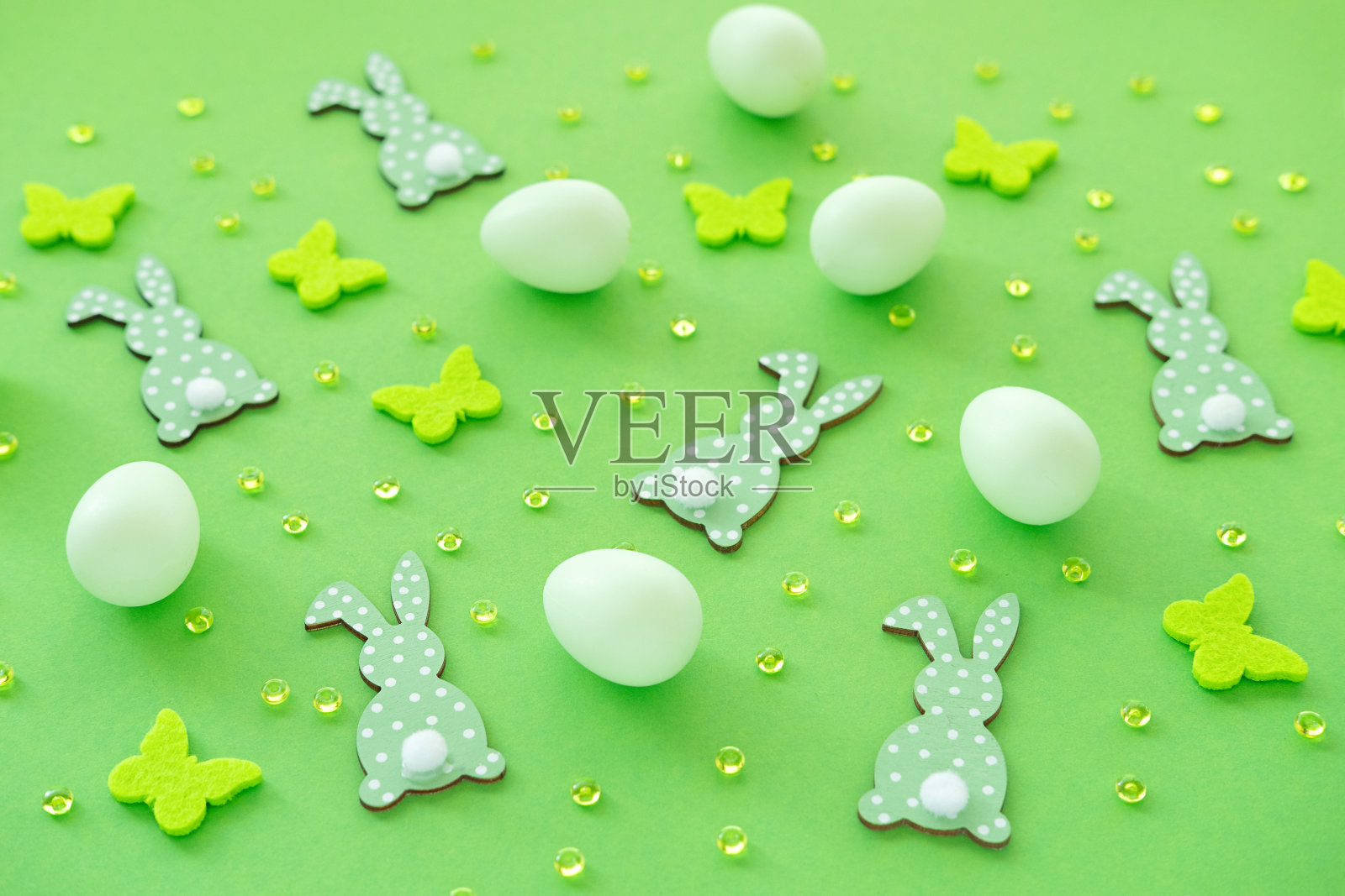 复活节彩蛋,绿色背景上有兔子和五彩纸屑。模式照片摄影图片