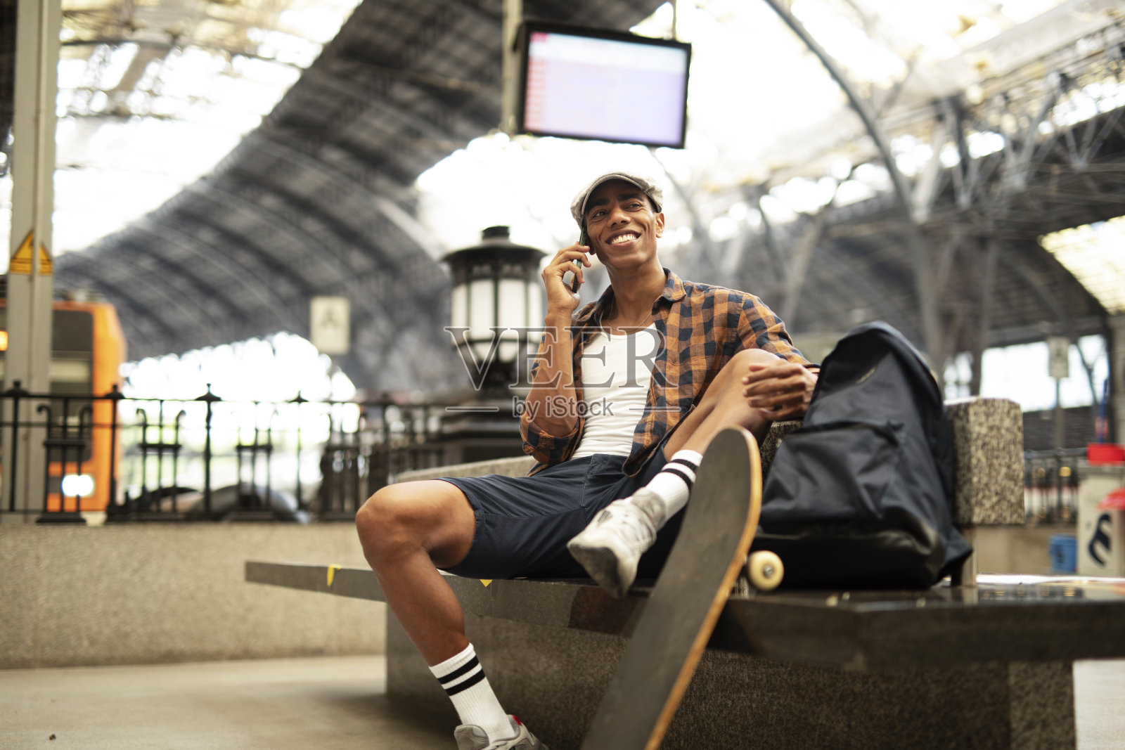 一个非洲男人在地铁里等车。男人对着电话说话照片摄影图片