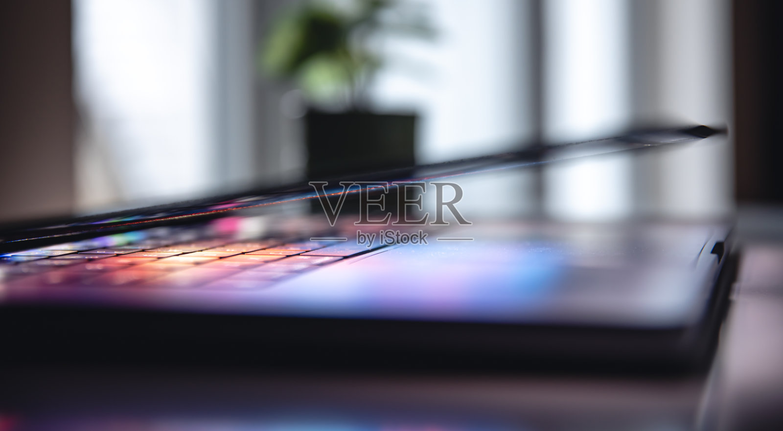 特写笔记本电脑键盘彩色霓虹灯照明,背光键盘。照片摄影图片