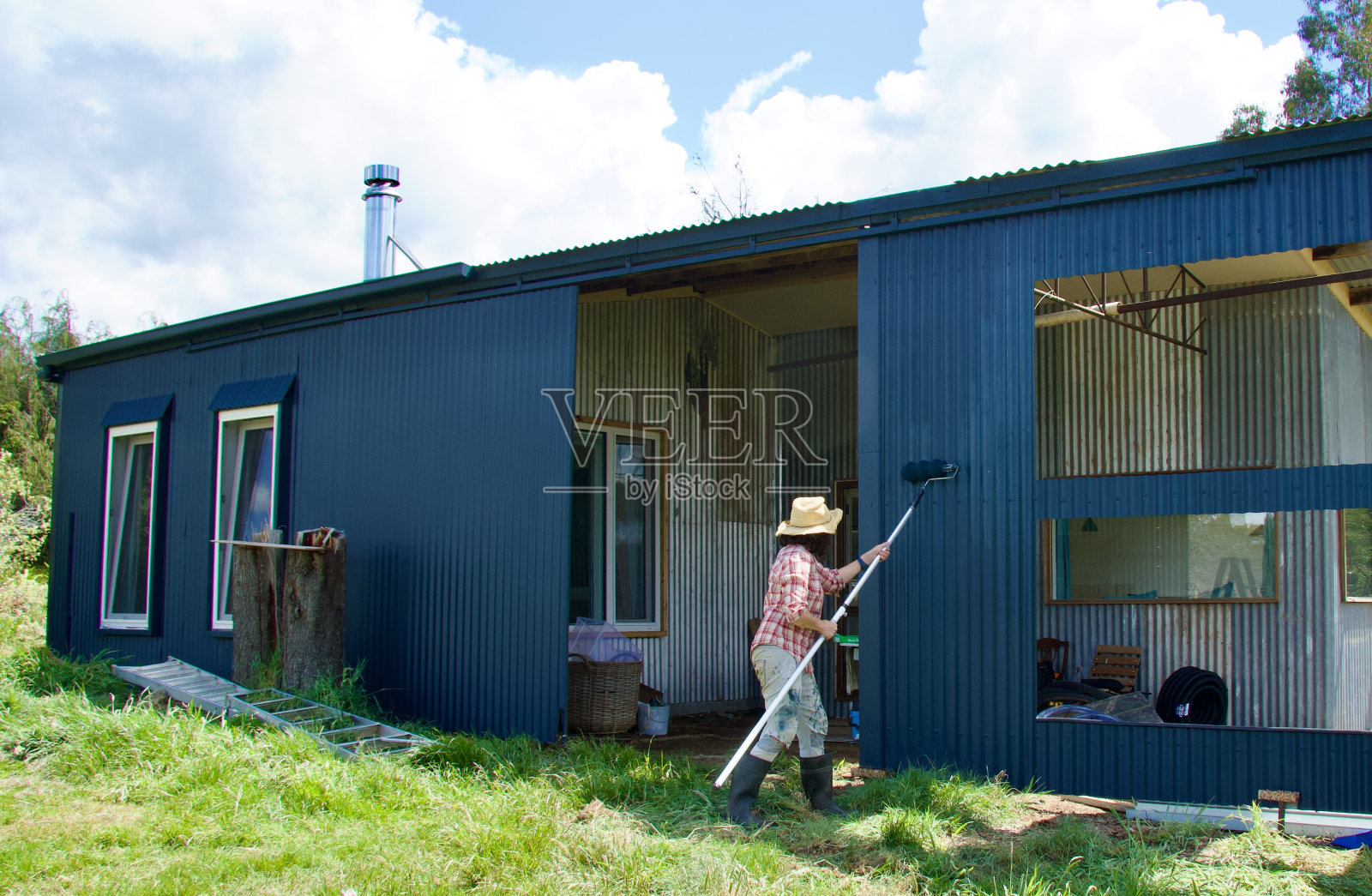 穿红衬衫的女人在棚子外面画画照片摄影图片