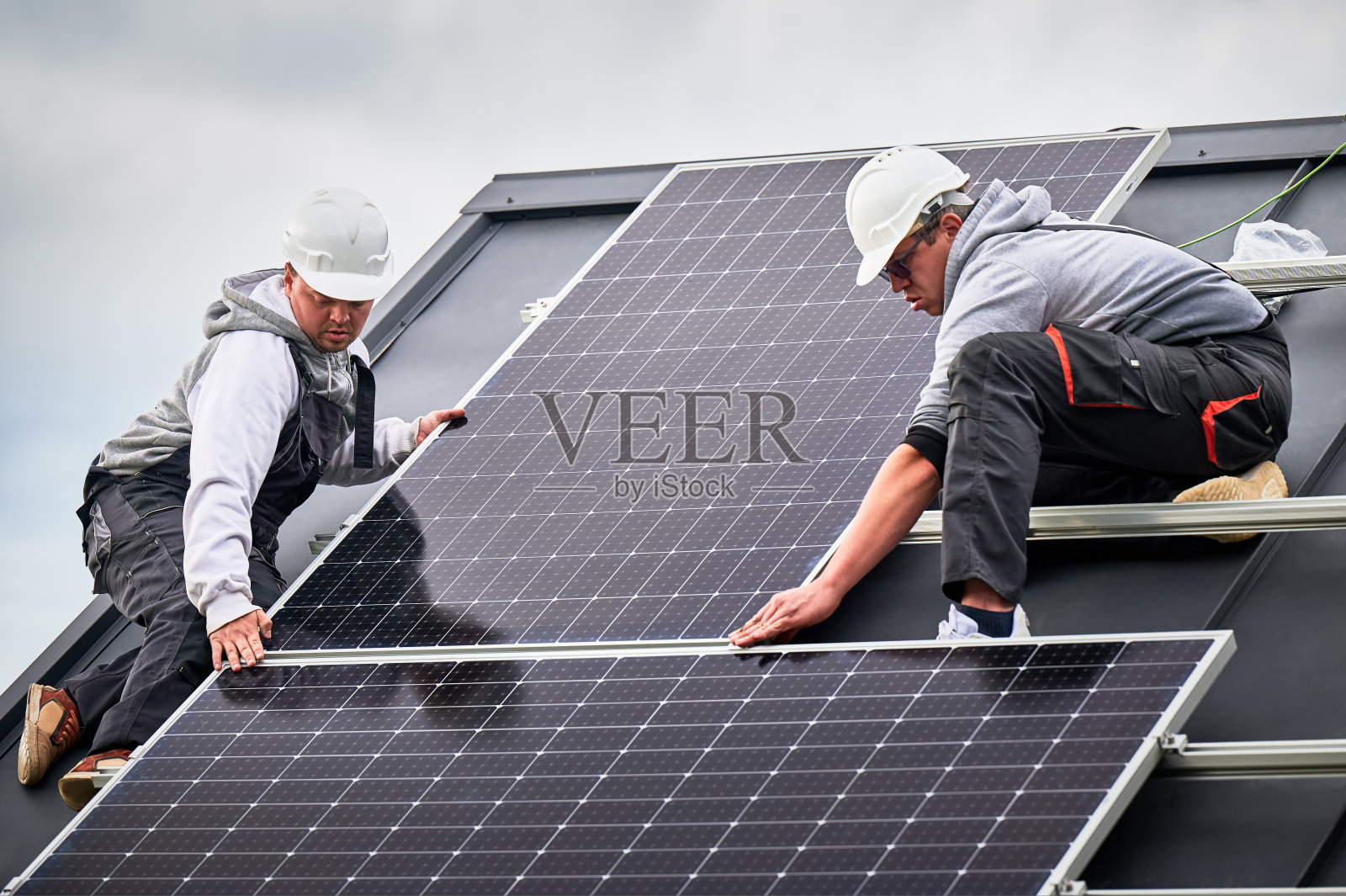 男工人在屋顶安装太阳能电池板。照片摄影图片