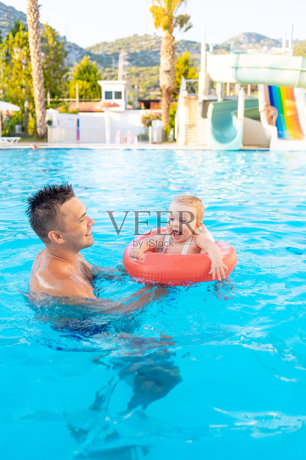 夏天,爸爸和宝宝在游泳池里的充气圈里游泳,放松,与家人共度时光照片摄影图片
