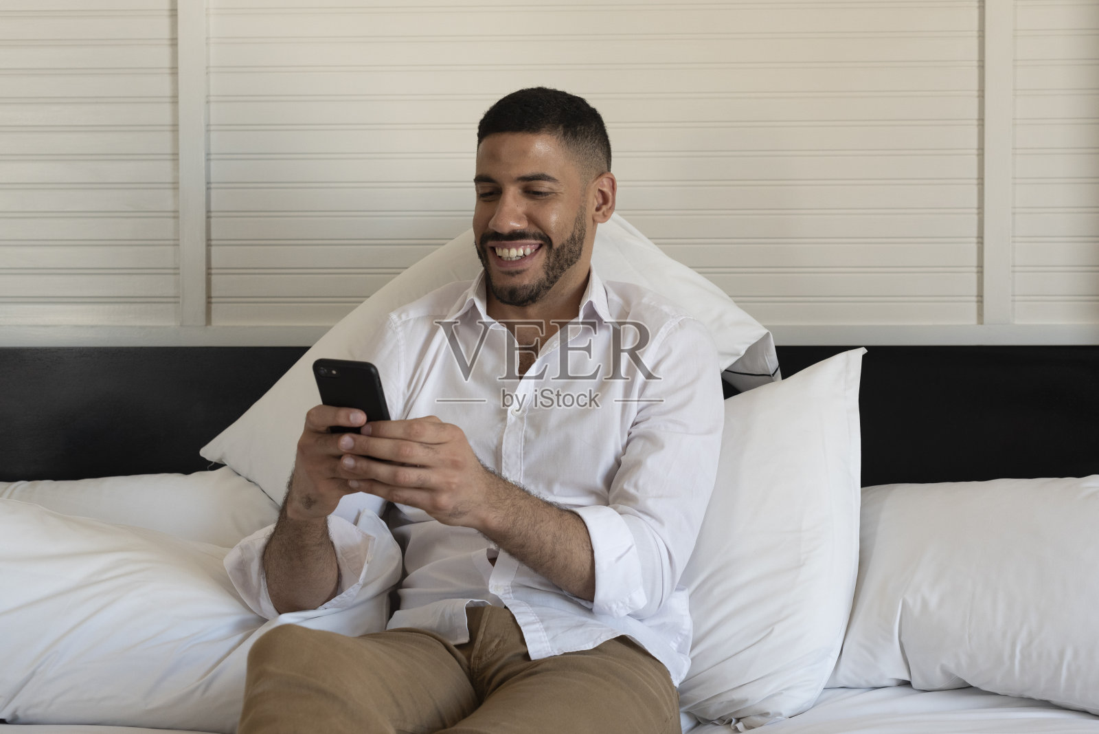 商人躺在酒店的床上使用智能手机照片摄影图片