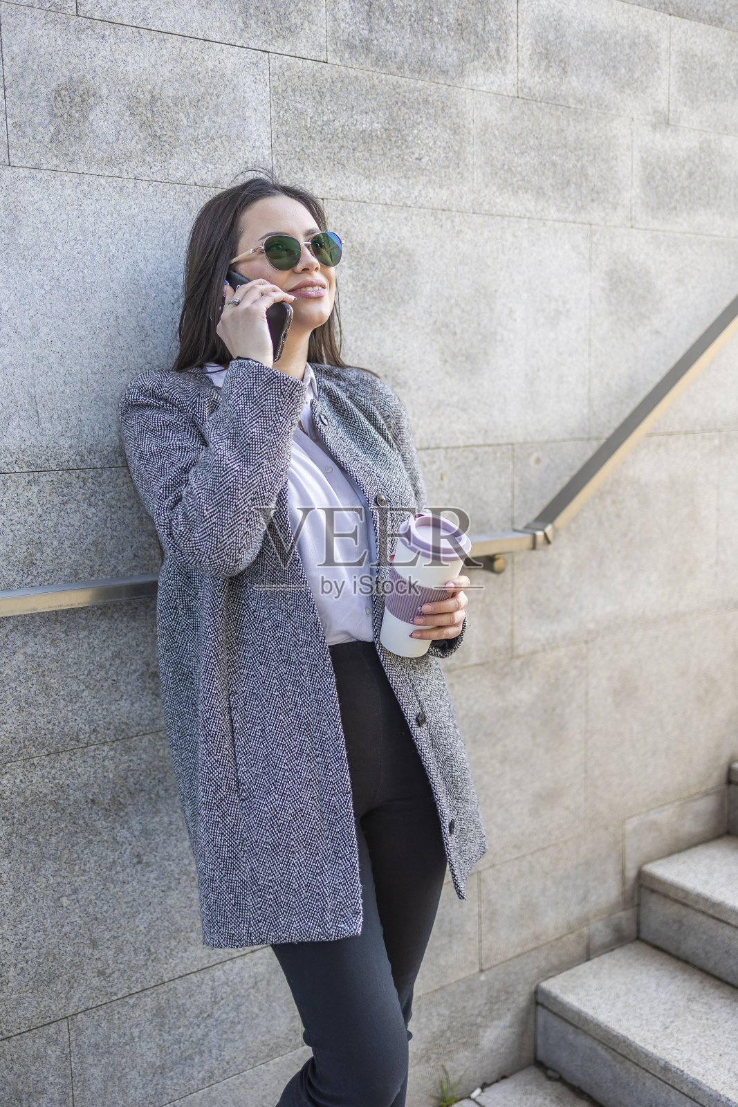 年轻的女商人一边喝咖啡一边用手机休息。照片摄影图片