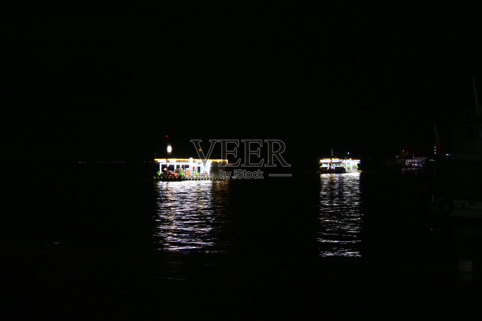 夜间,在巴西繁忙的玛瑙斯港口,亚马逊河上两个漂浮加油站的反光。照片摄影图片