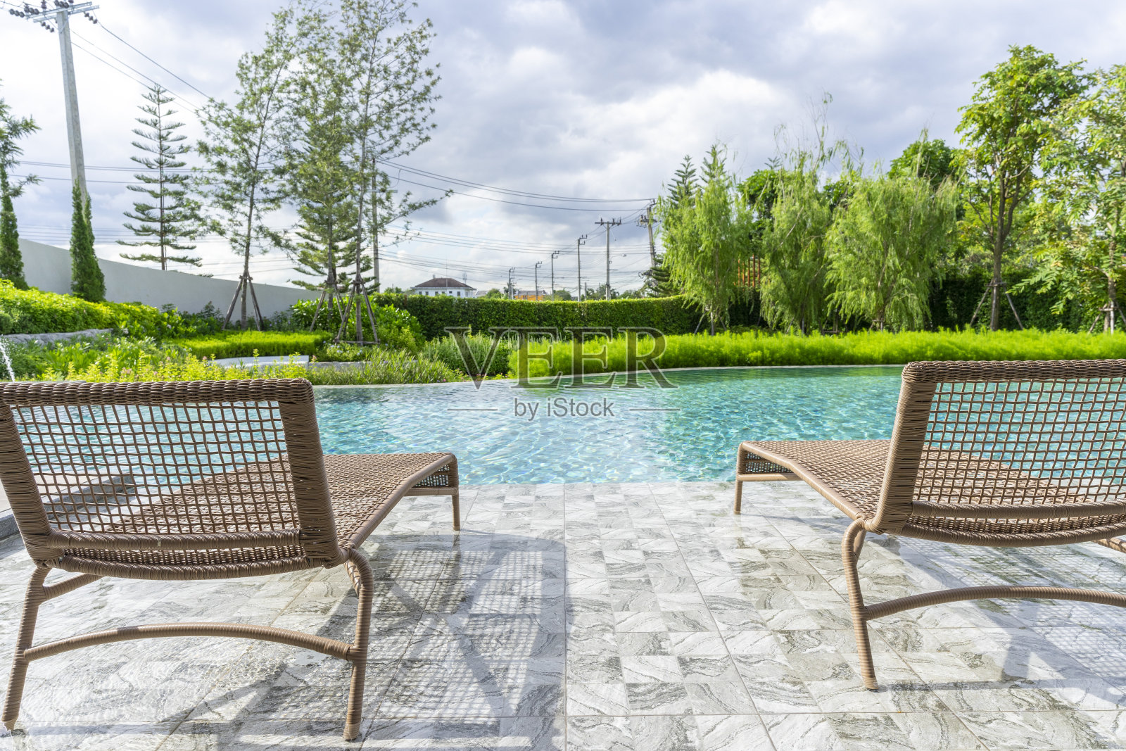 在游泳池里的木地板上放着木制沙发床,有蓝天。照片摄影图片