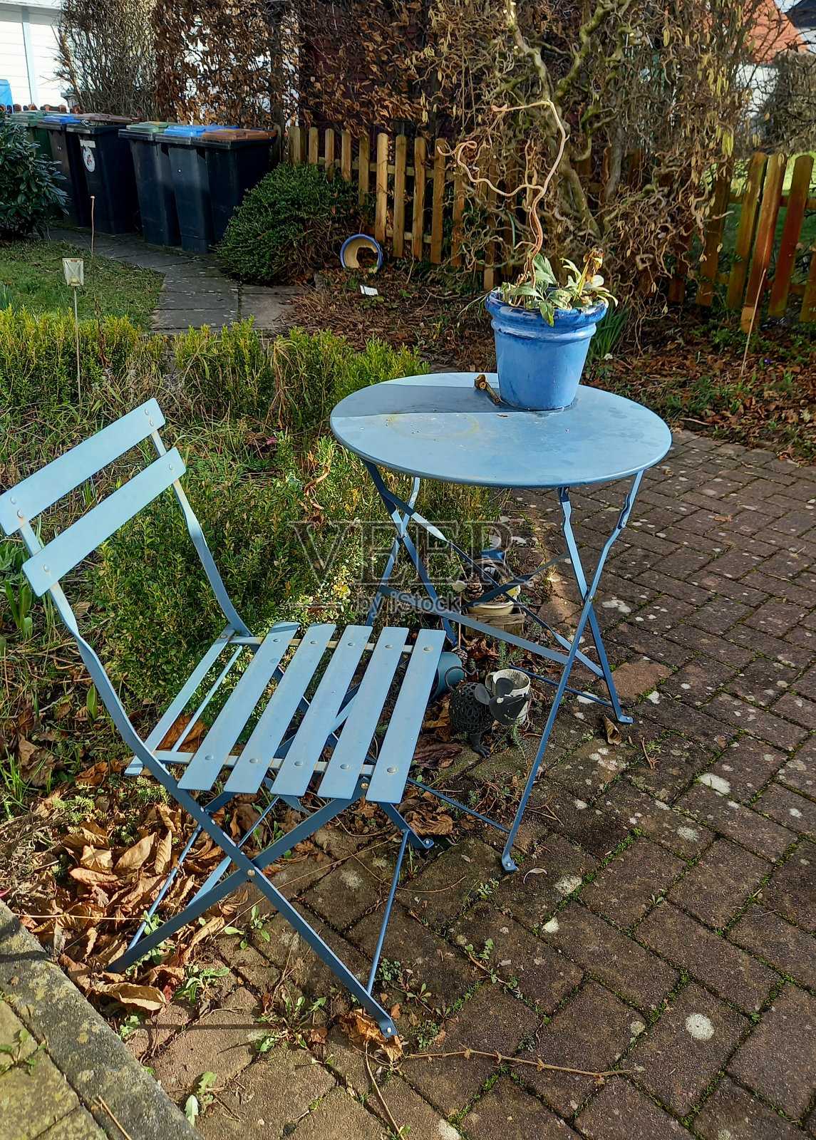 一张蓝色的圆桌和一把蓝色的椅子在前院垃圾桶的背景里照片摄影图片