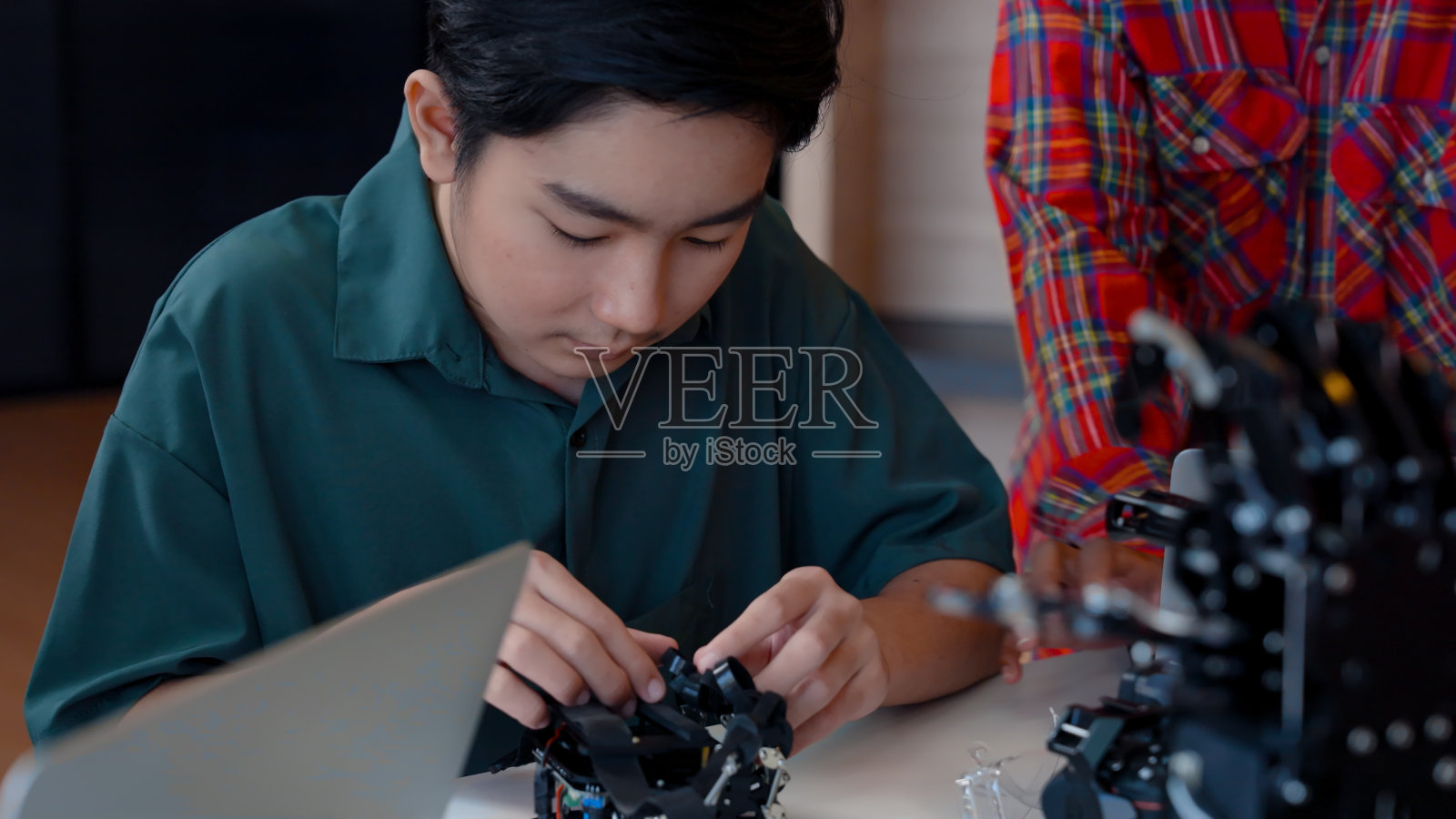 学生正在试着把他的手指放在手指环上的机械手,那是由人类创造的控制机械手的机械手,孩子正在试着学习使用机械手,一步步戴上手指手触摸系统。照片摄影图片