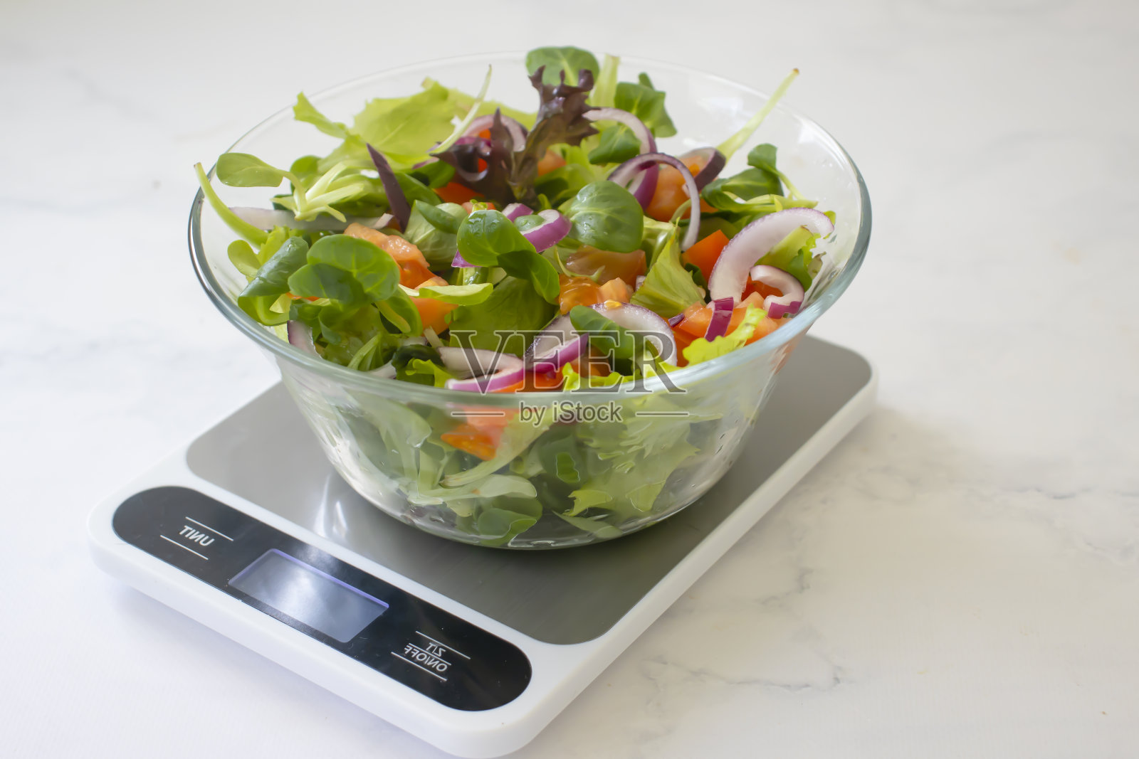 盘子里放着沙拉,厨房的天平放在浅色的背景上照片摄影图片