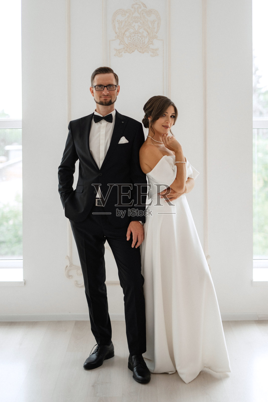 新郎系着黑色西装领带,新娘在明亮的画室里照片摄影图片