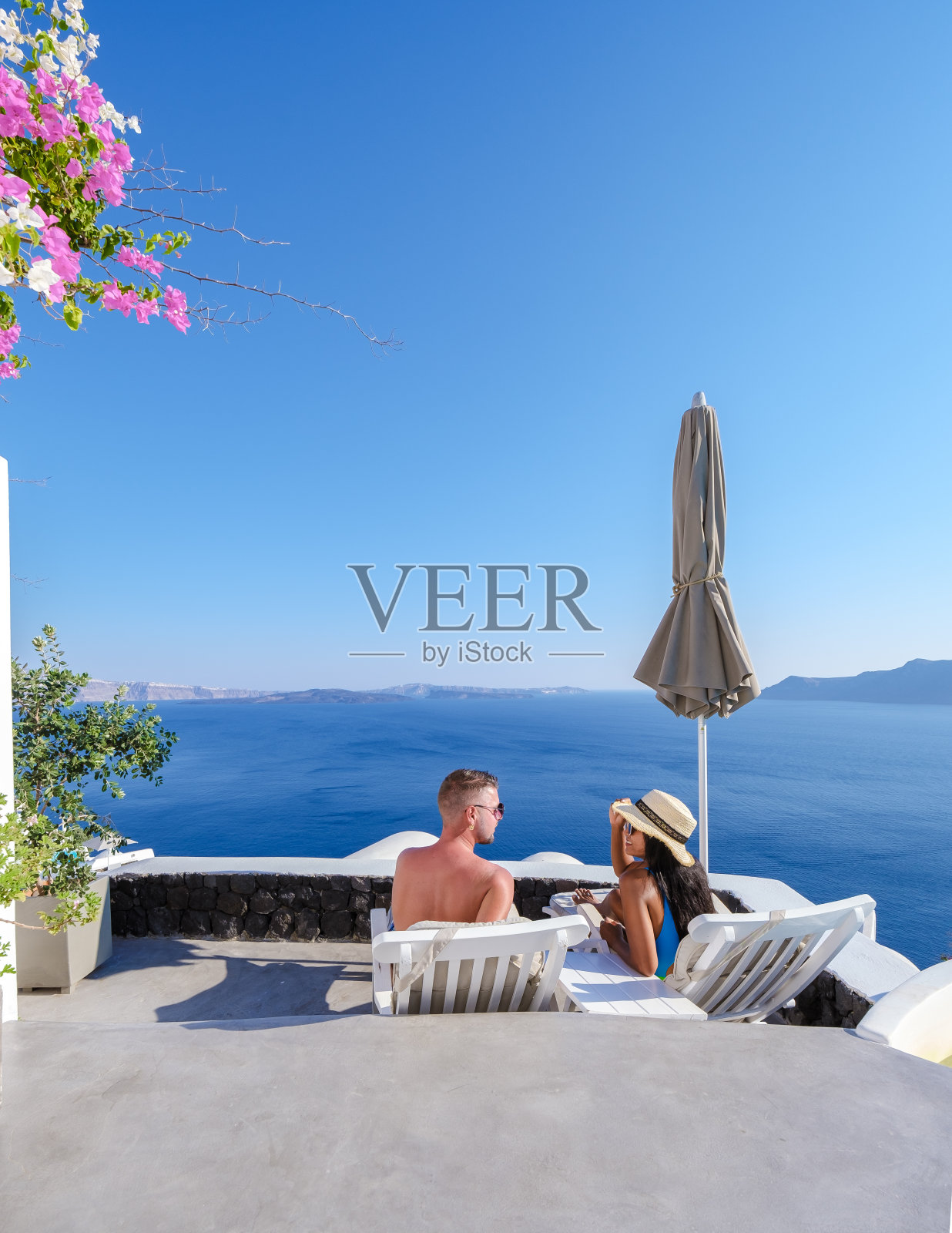 在圣托里尼岛度假期间,男男女女参观了粉刷成白色的希腊村庄伊亚照片摄影图片