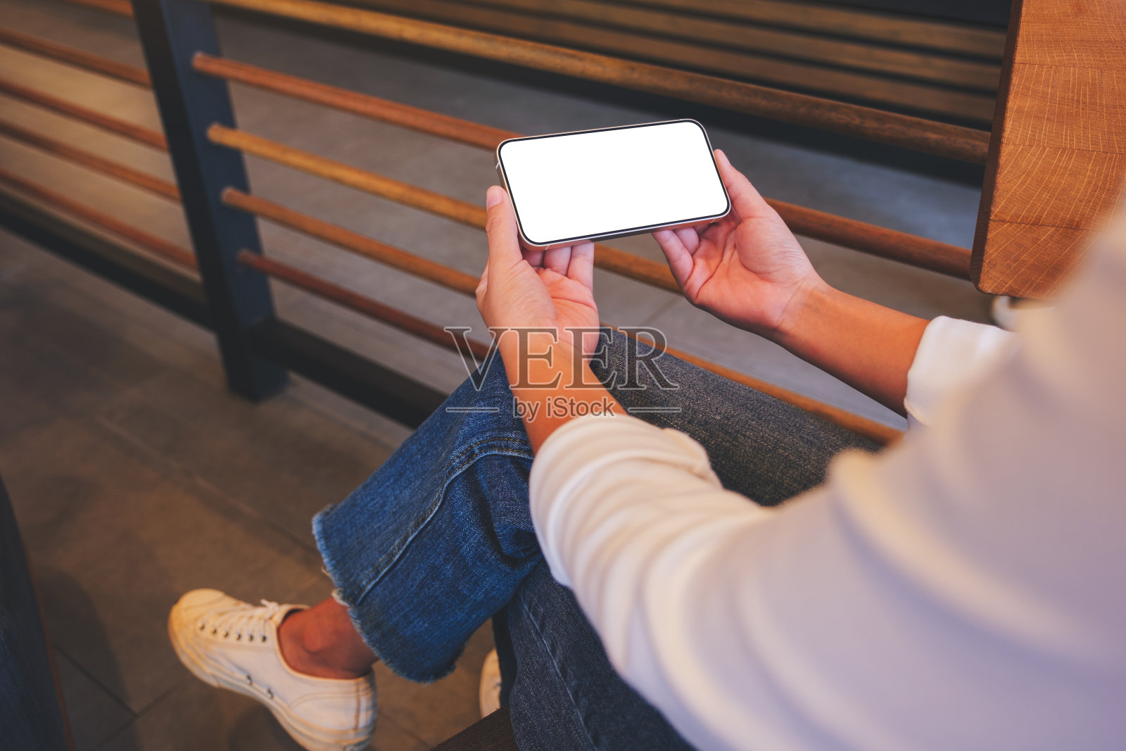 一个女人在咖啡馆里拿着空白桌面的手机的模型图像照片摄影图片