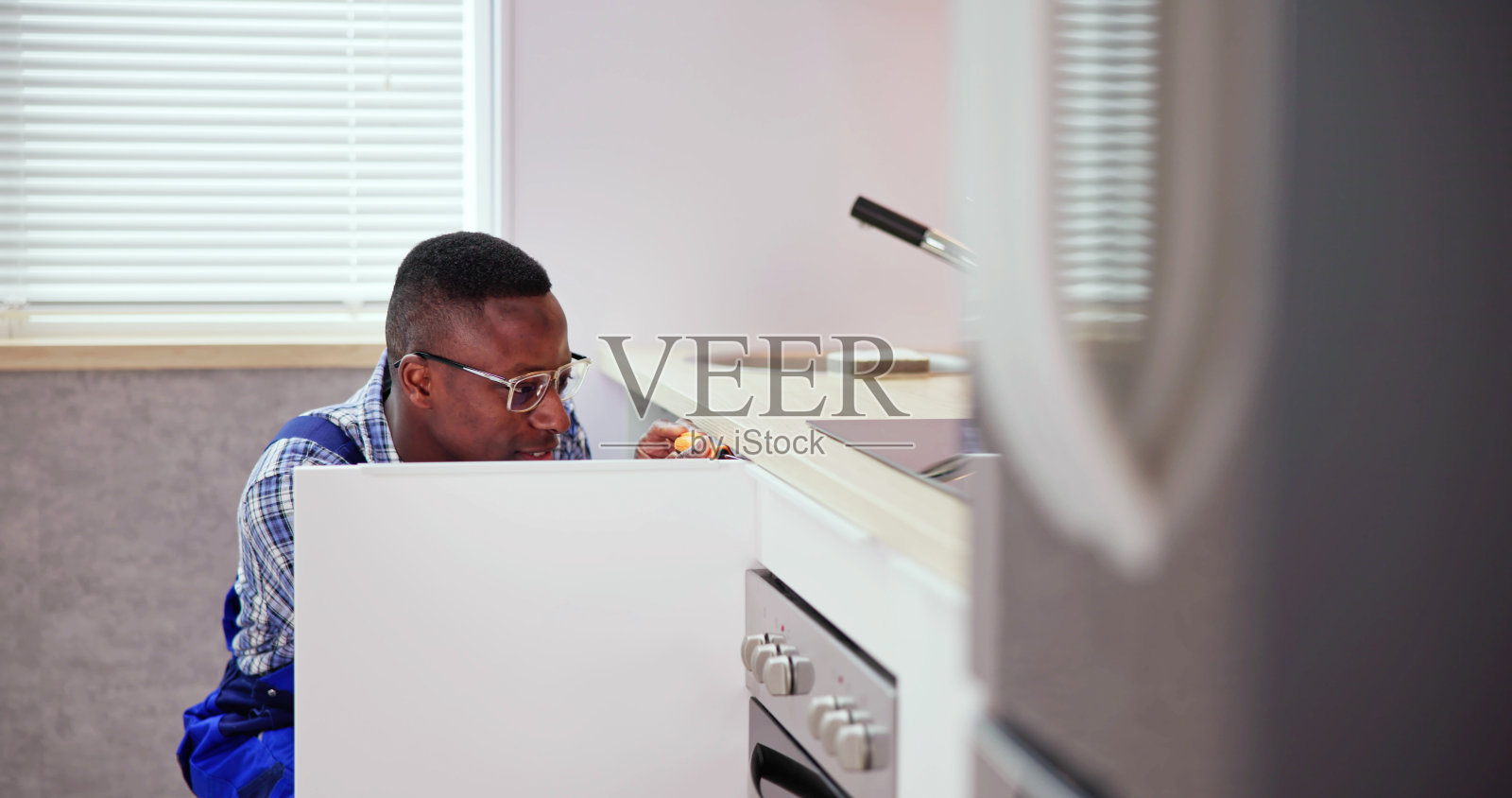 穿着工作服的修理工正在修理橱柜铰链照片摄影图片