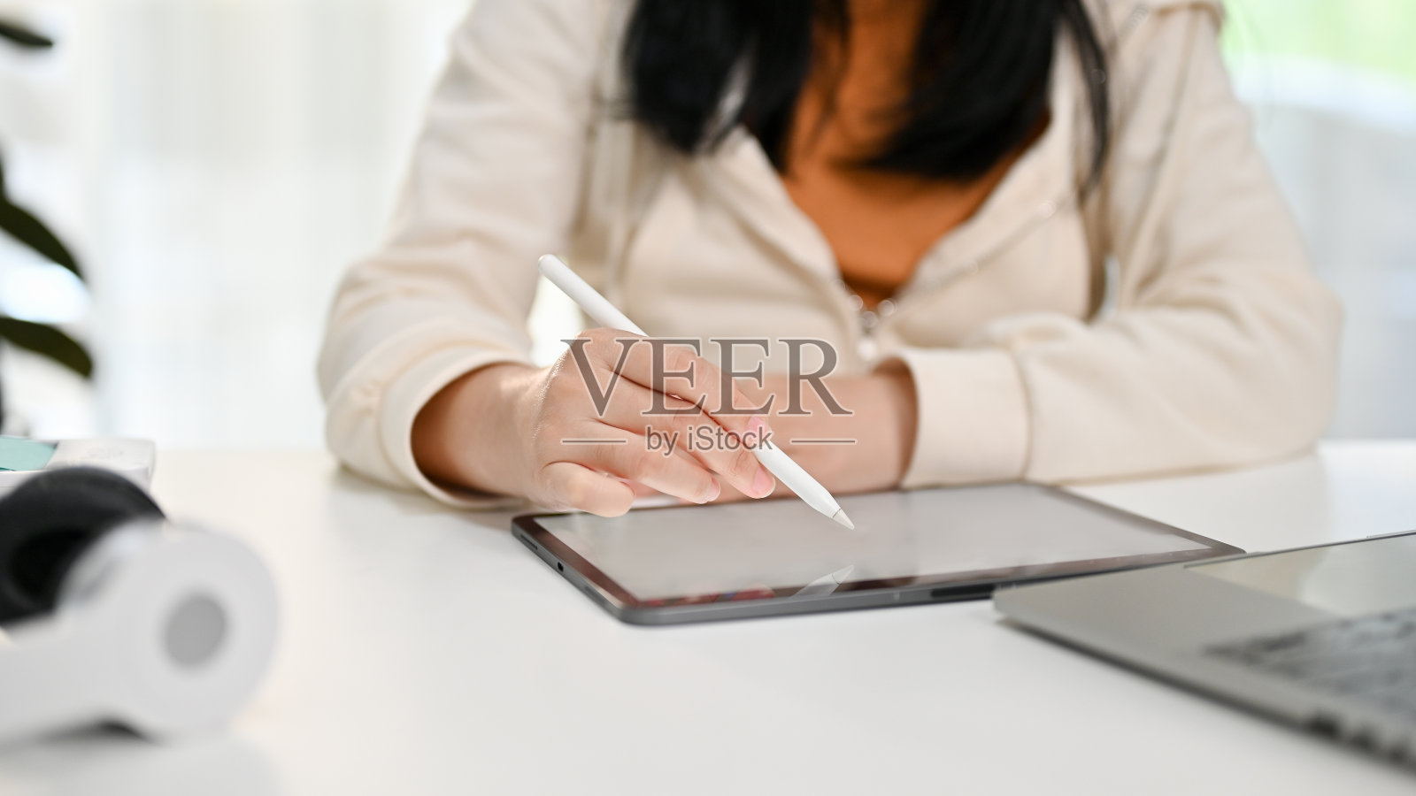 一名亚洲妇女在她的办公桌上使用她的数字平板电脑的裁剪图像。照片摄影图片