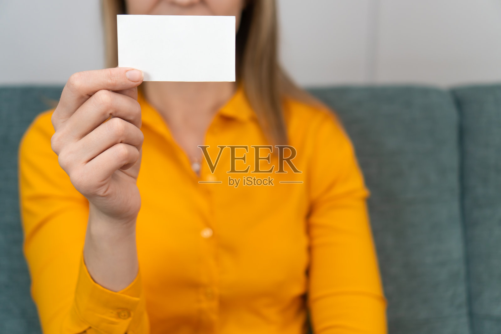 一个戴眼镜、穿橙色衬衫的女人手里拿着一张白色名片的特写。专家提供服务照片摄影图片