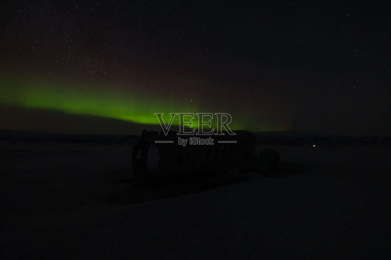 在冰岛著名的飞机失事现场,令人惊叹的自然现象被称为北极光。照片摄影图片