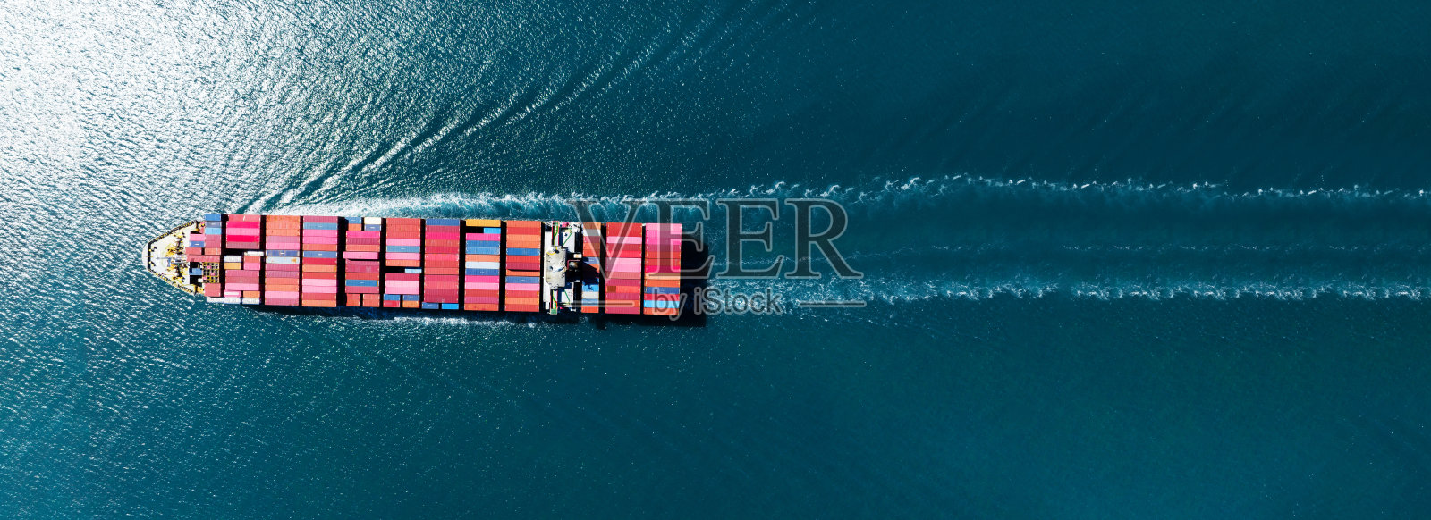 载有集装箱的货船和拖船的俯视图,为从集装箱堆场港口到海关的出口进口货物快速运行,海洋中的飞机尾迹线照片摄影图片