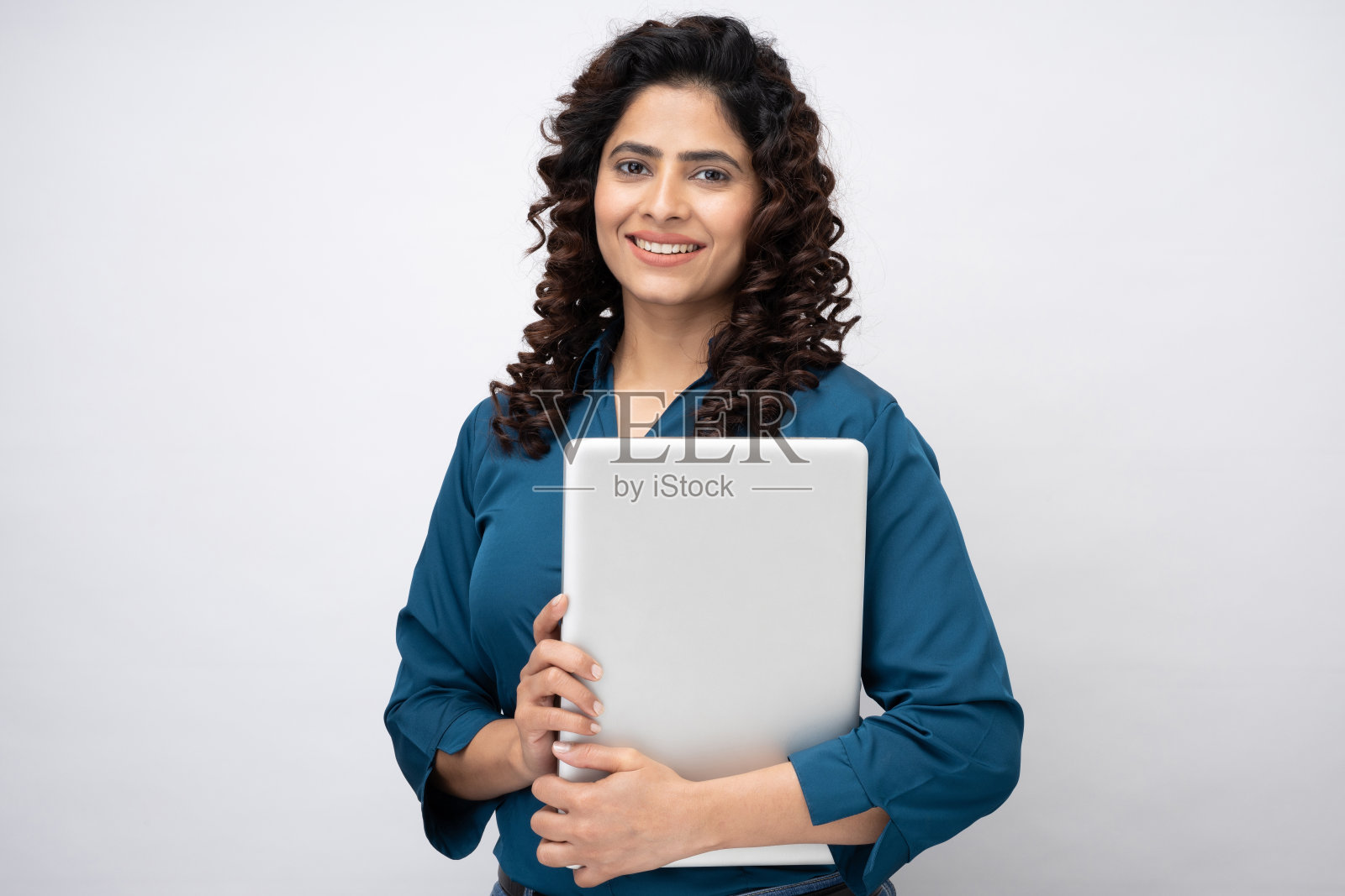 微笑的年轻女商人拿着笔记本电脑,看着相机在白色背景的股票照片照片摄影图片