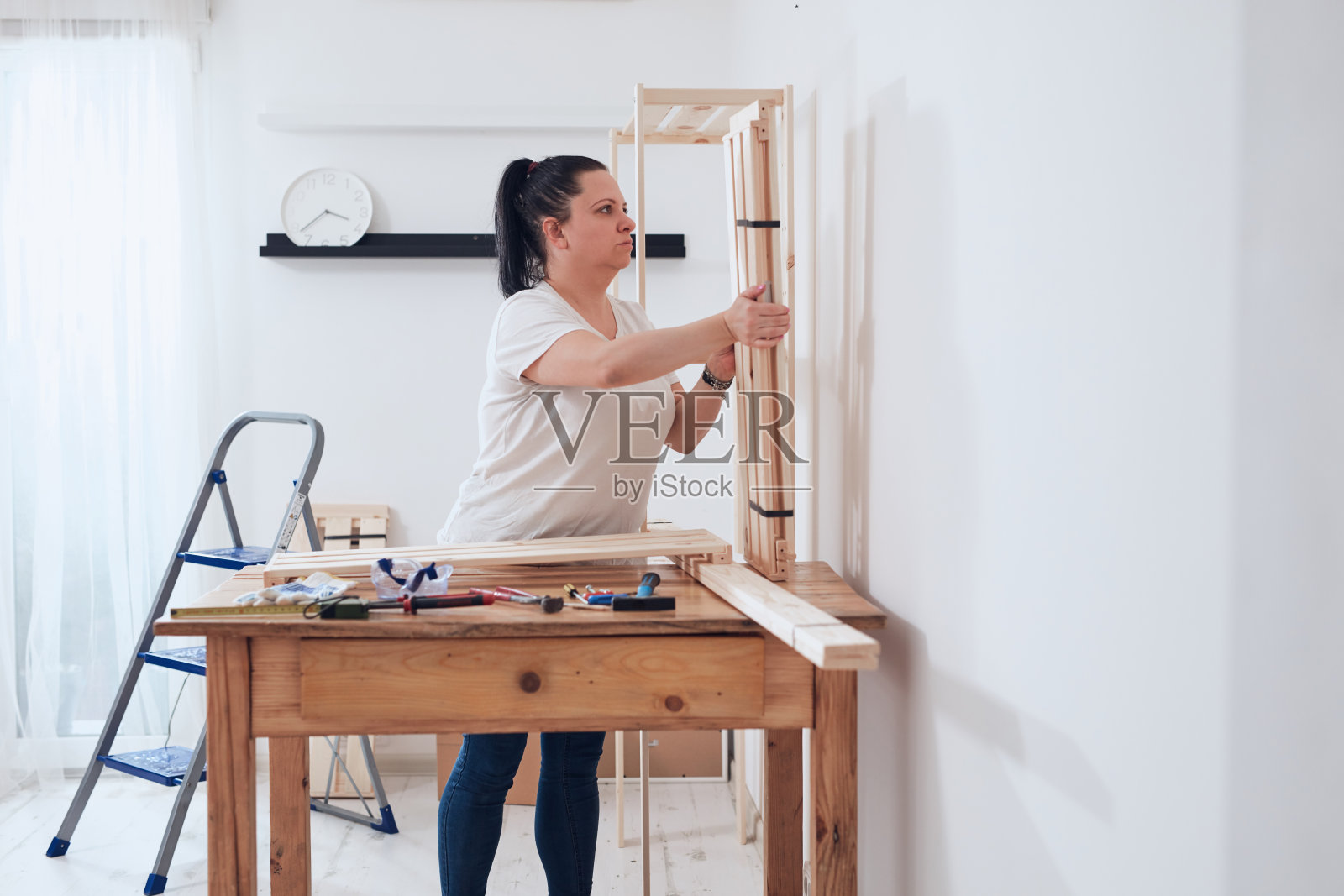 在公寓里组装新木架和家具的女人。照片摄影图片