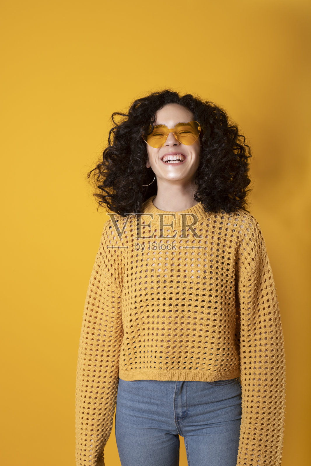 笑女孩卷曲的黑色头发和时尚眼镜在黄色背景照片摄影图片